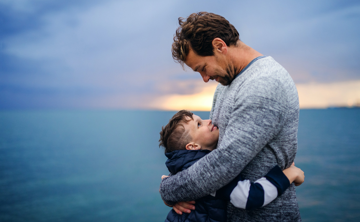 father and son hug by the water