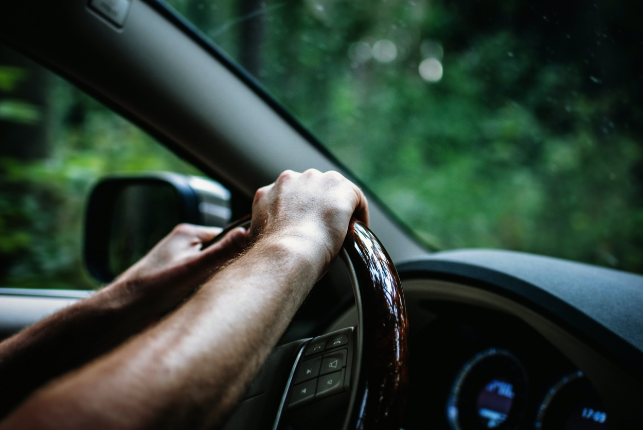 man holding steering wheel driving