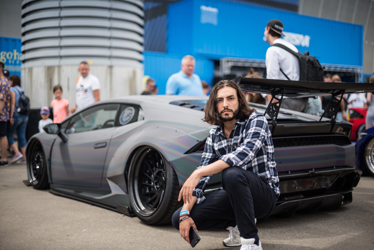 man sitting in front of a supercar