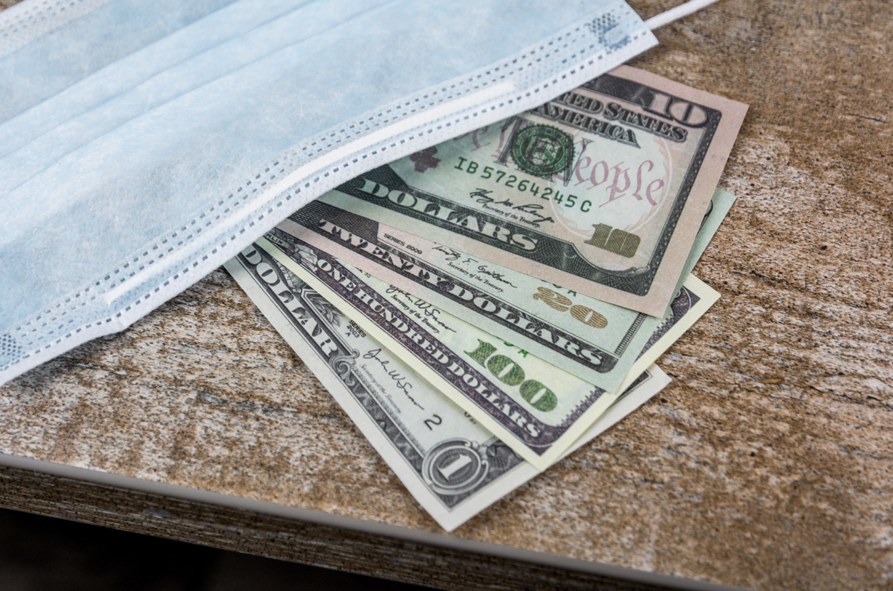 medical mask with dollars on a wooden table