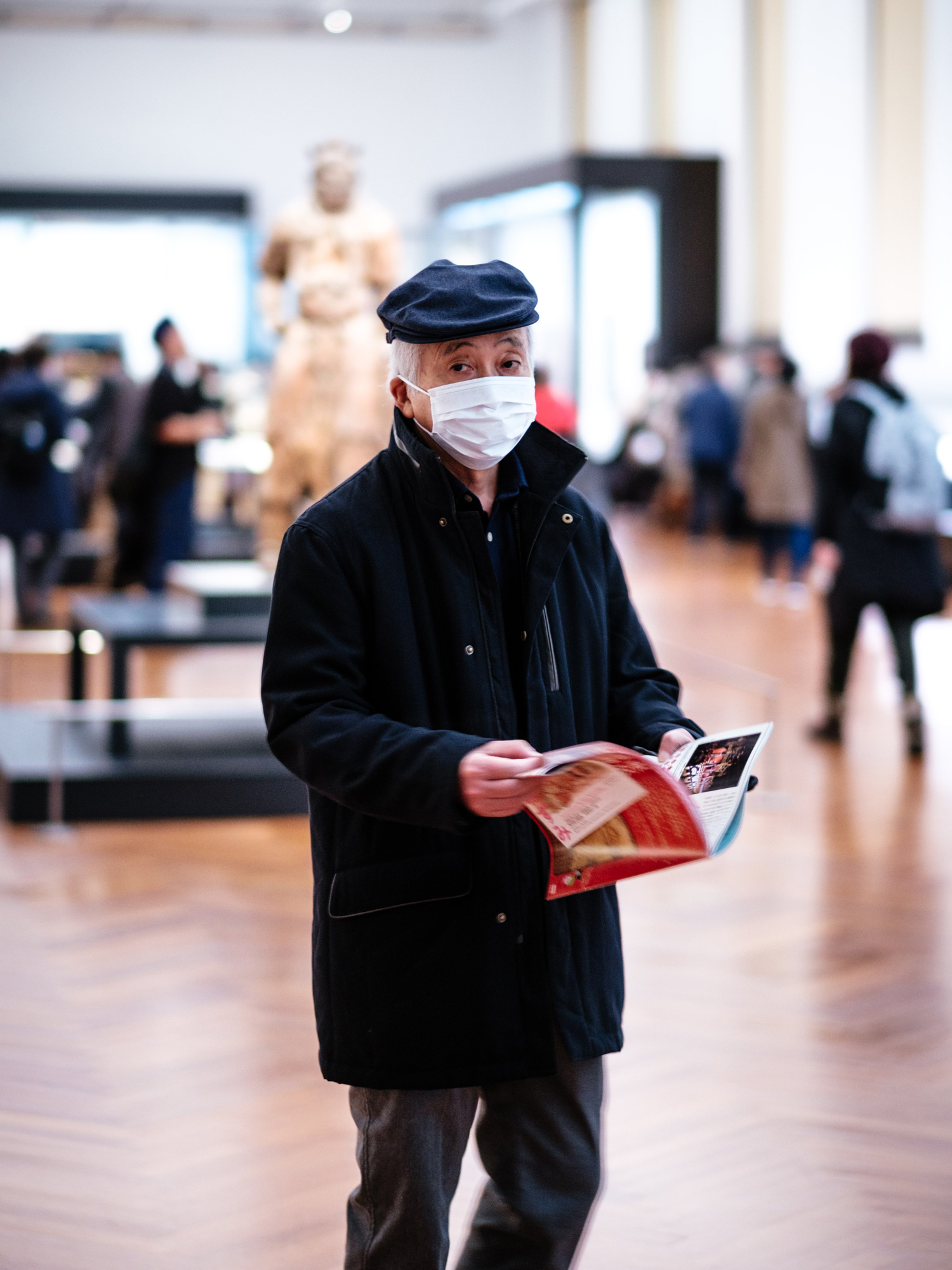 older man wearing mask holding a magazine