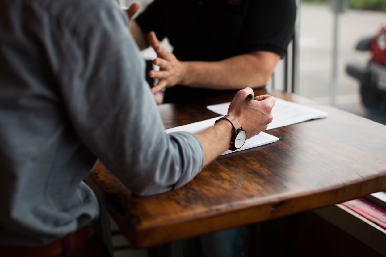 two people doing paperwork sitting by a wooden table