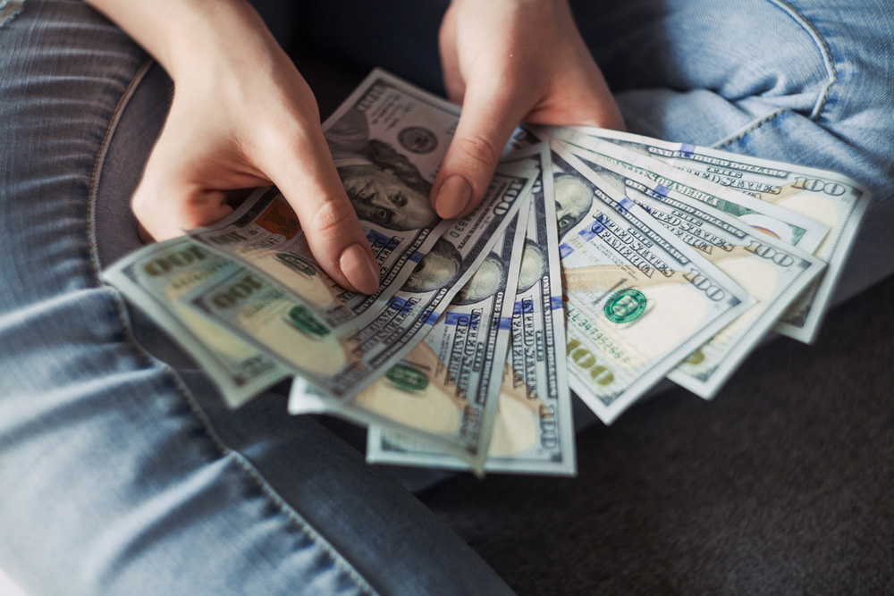 woman holding hundred dollar bills