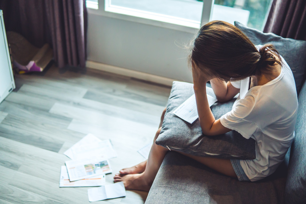 woman sitting on the couch worried about bills