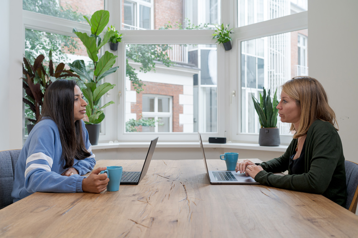 two women sitting at a table working on their laptops